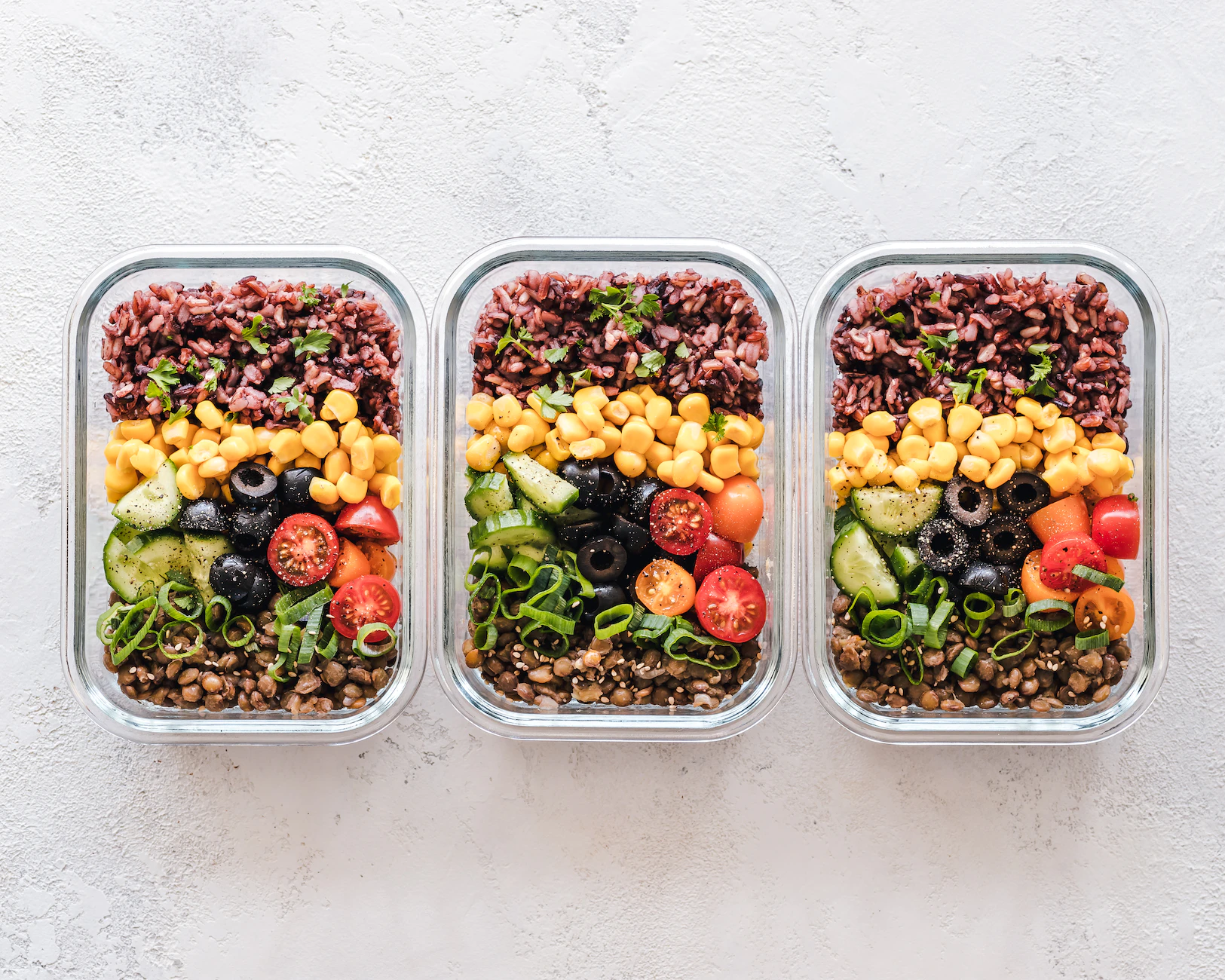 three glass food containers with a variety of vegetables and grained for meal prep