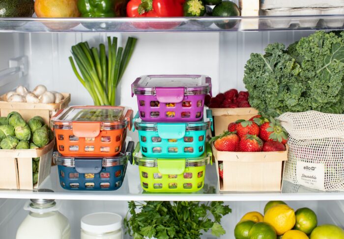 a fridge filled with fresh produce neatly organised in colourful containers and eco-friendly packaging