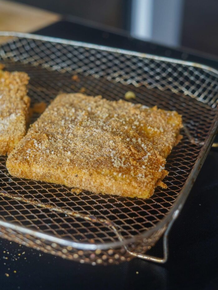 Battered and breaded marinated tofu on an air fryer tray.