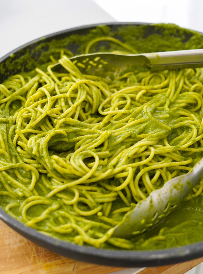 a big pan of spaghetti with a bright green sauce