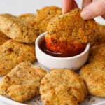 a vegan chicken nugget being dipped into a red chili sauce