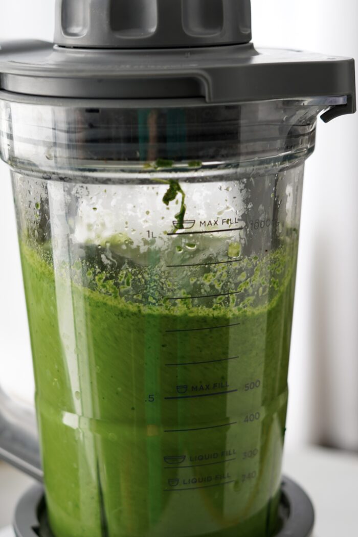 a blender full of a bright green sauce