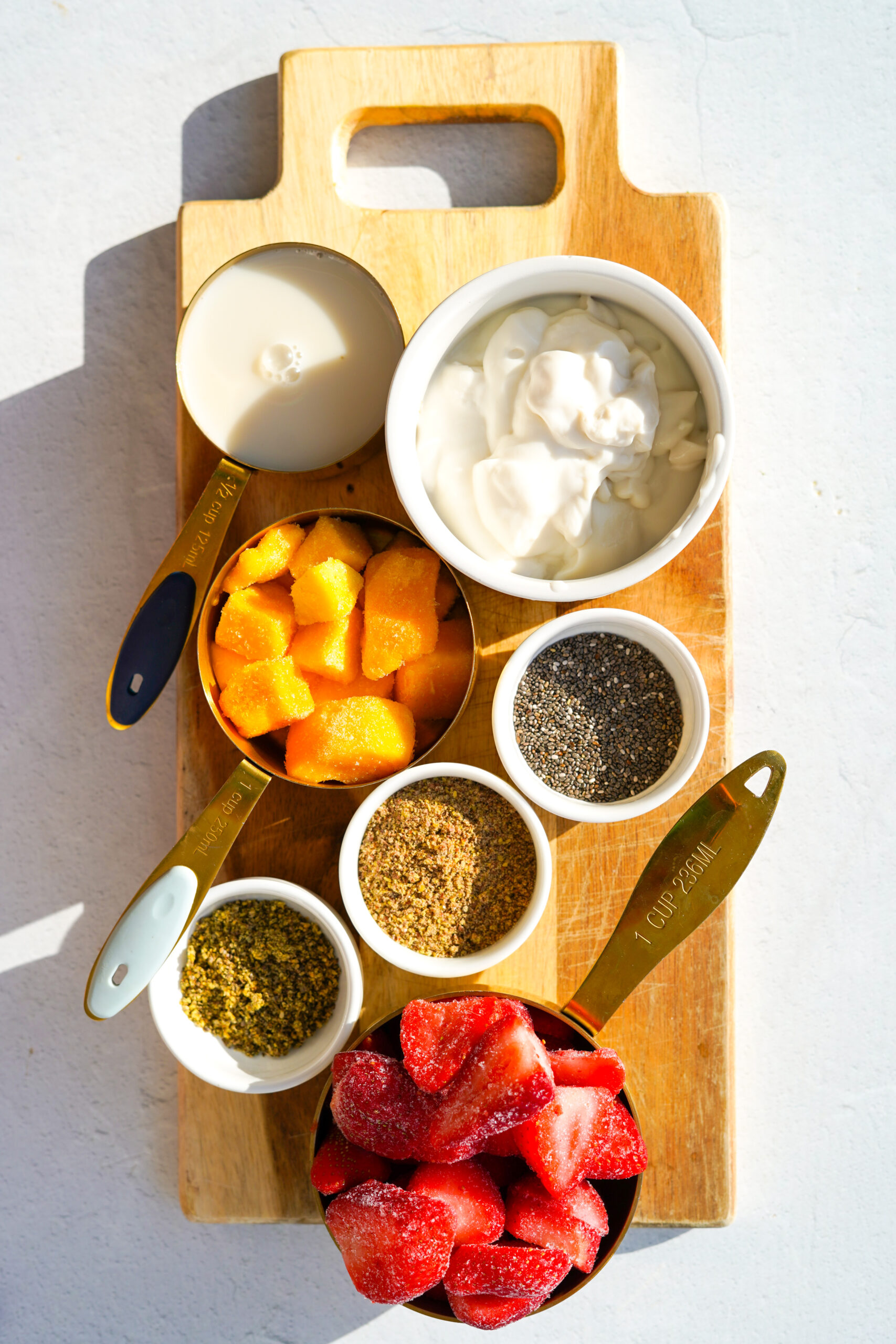 pink smoothie ingredients on a wood cutting board