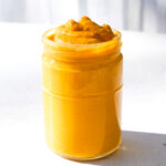 a bright yellow jar of vegan nacho cheese sitting on a white countertop