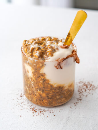 mixed chocolate and coffee overnight oats with a gold spoon sitting on a white table