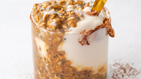 mixed chocolate and coffee overnight oats with a gold spoon sitting on a white table