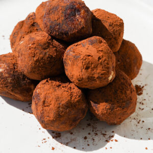 chocolate coated truffles sitting on a white plate