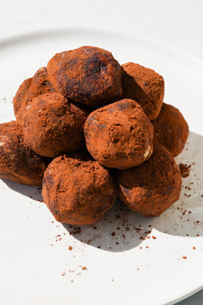 chocolate coated truffles sitting on a white plate