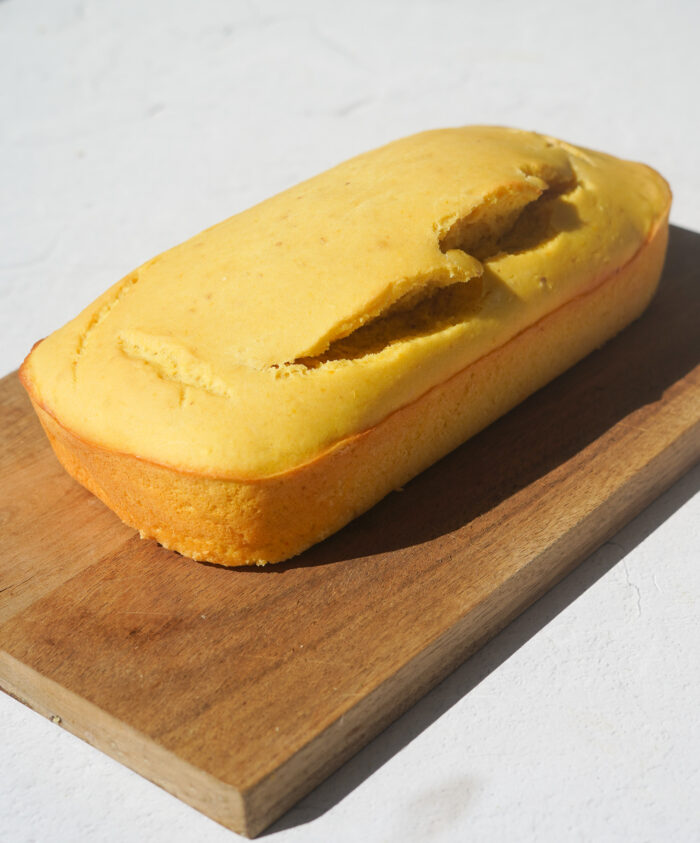 Lemon Loaf freshly baked, on a wooden cutting board with natural sunlight