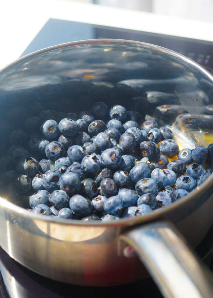 blueberries sitting in a silver sauce pan with maple syrup