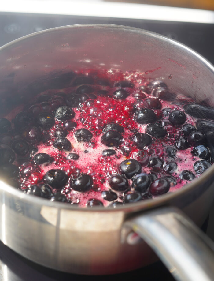 blueberries boiling in a sauce pan with maple syrup