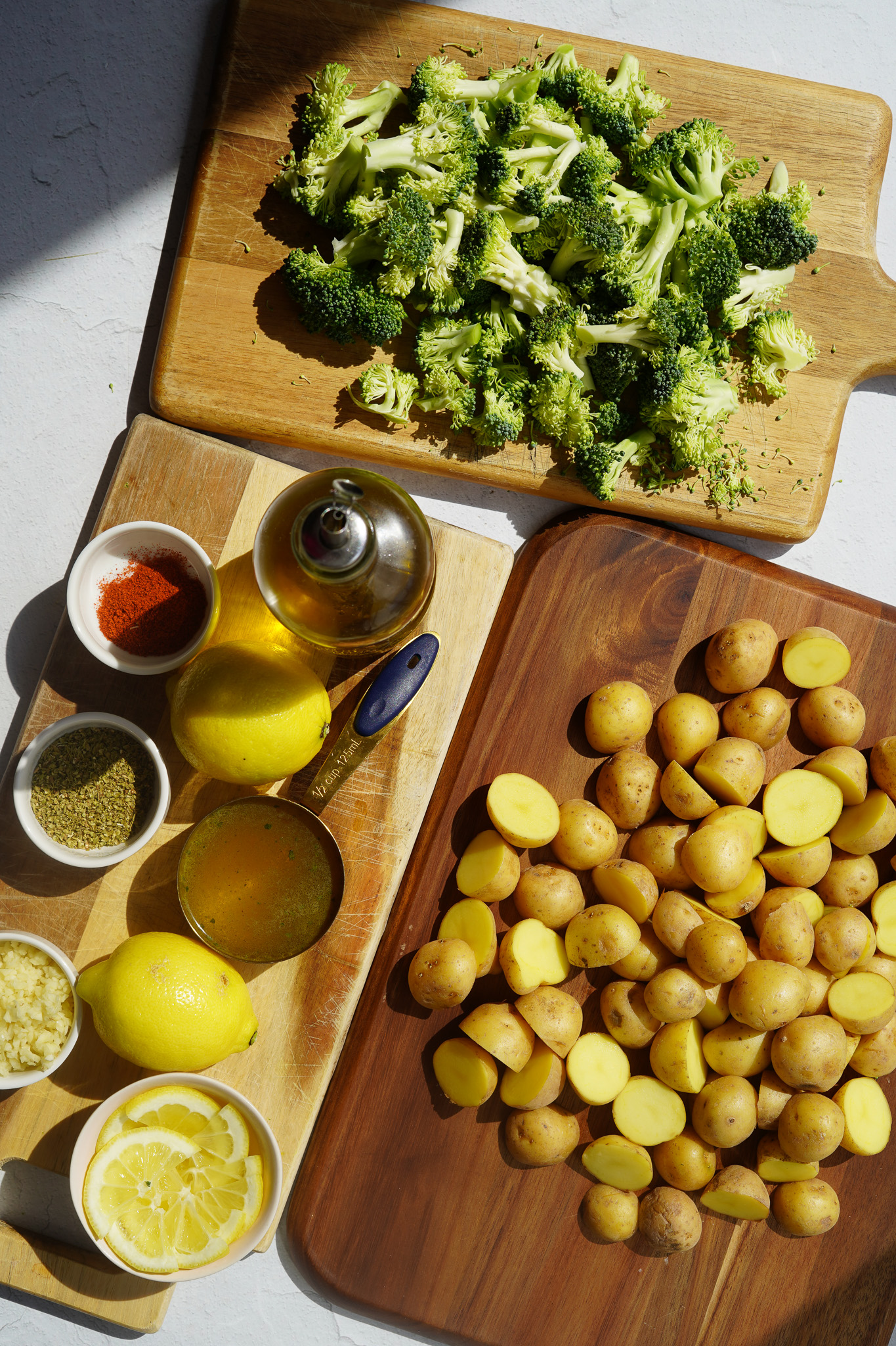 an overhead shot with ingredients for greek lemon potatoes including sliced mini potatoes and broccoli on a cutting board