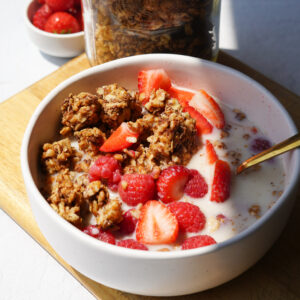 Easy Homemade Healthy Granola served in a white bowl with strawberries and yogurt