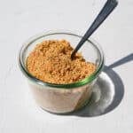 homemade vegan breadcrumbs on a glass dish with metal spoon on a white counter