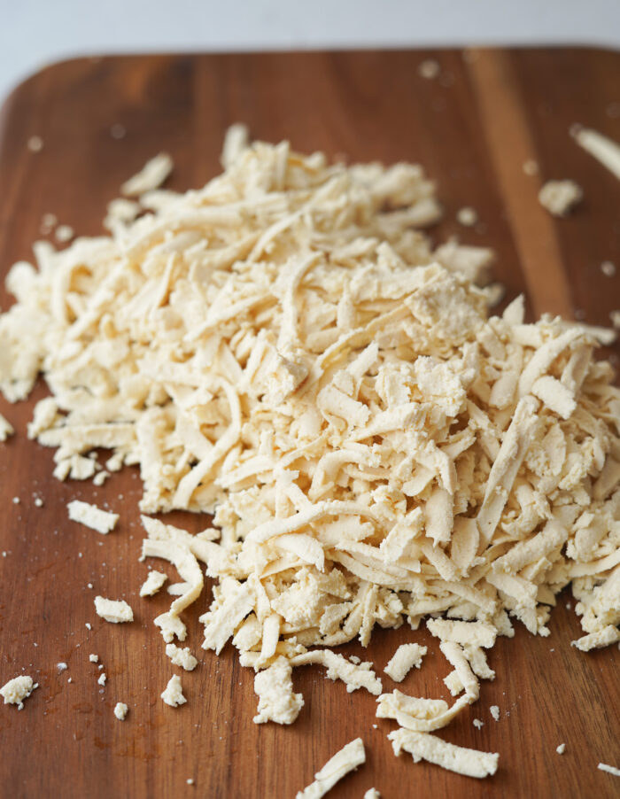 grated tofu on a wooden chopping board