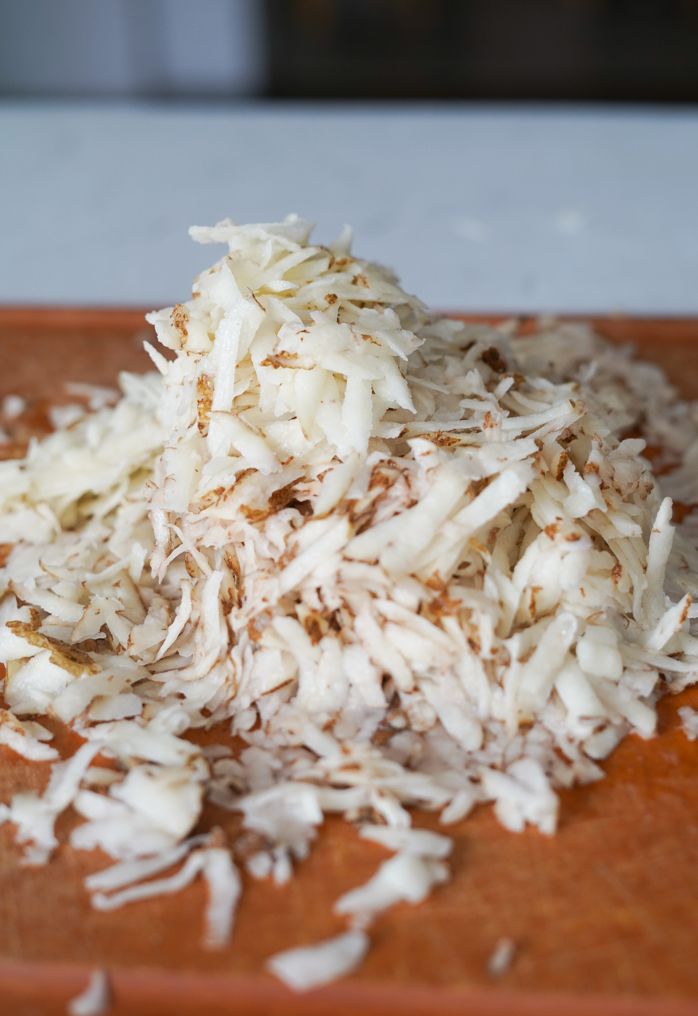 grated potatoes on a wooden cutting board