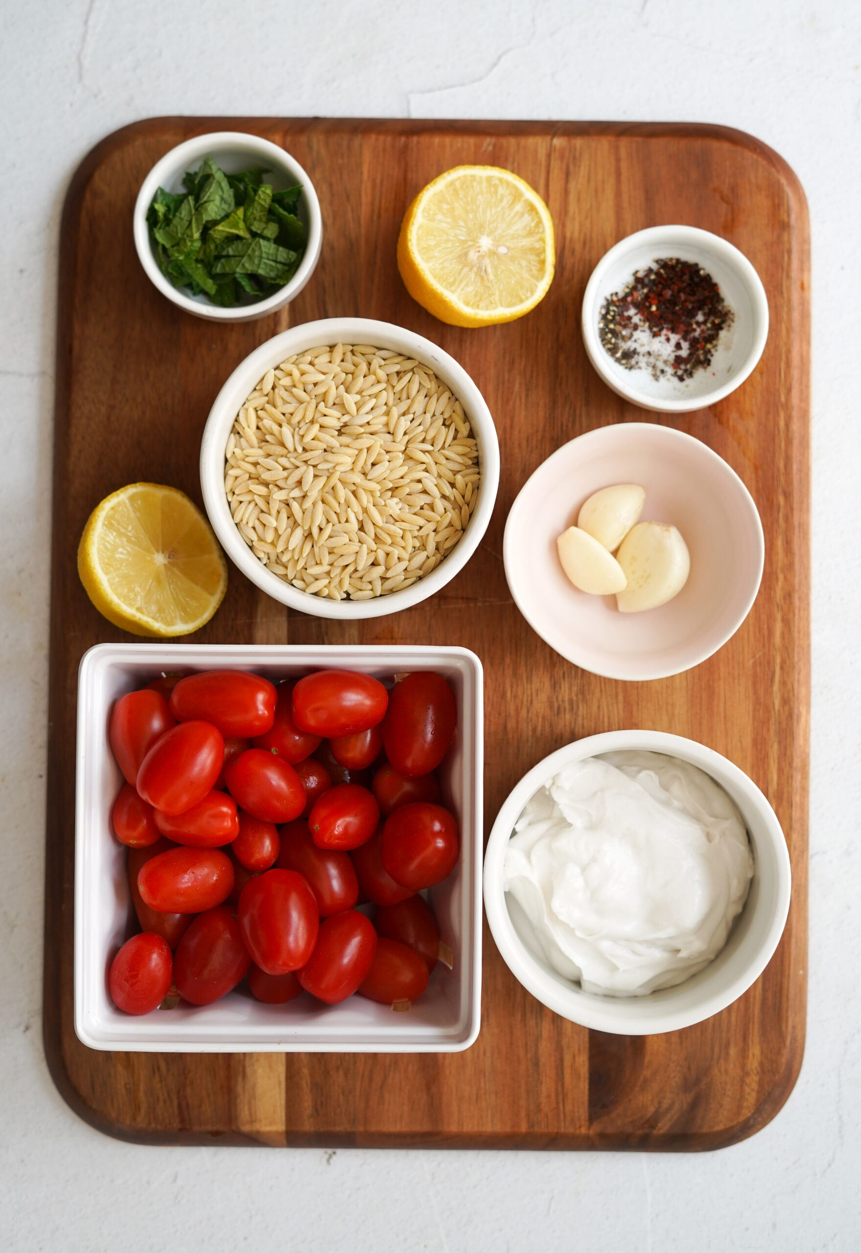 tomato orzo ingredients laid out on a wooden cutting board