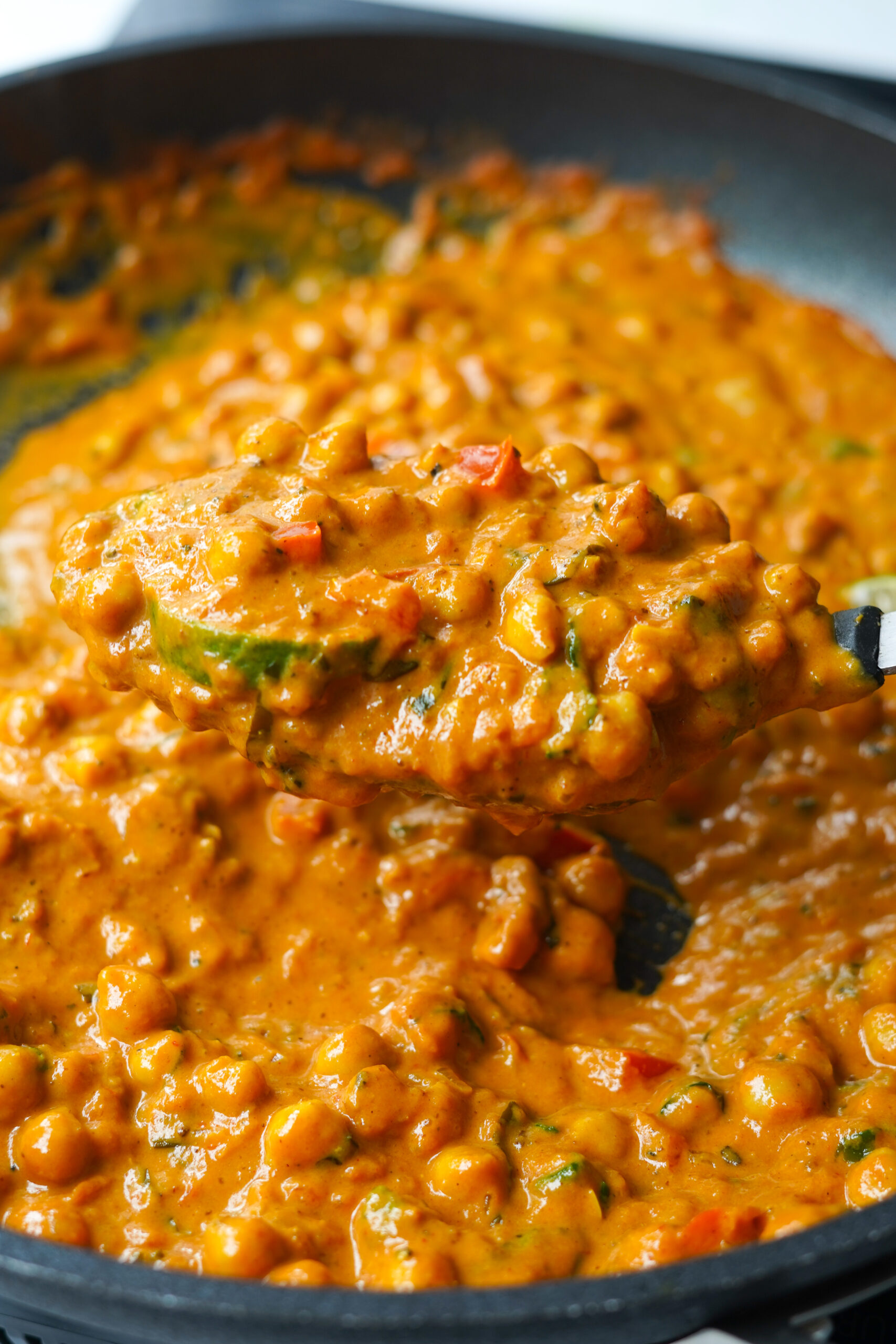 a spoonful of peanut butter curry lifted out of the pan