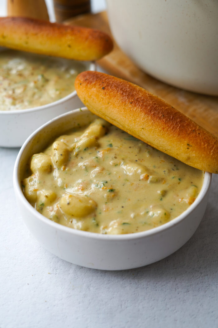 vegan Olive Garden gnocchi soup served in a white bowl with a breadstick