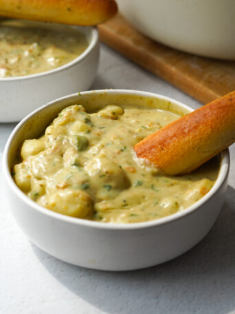 vegan Olive Garden gnocchi soup served in a white bowl with a breadstick
