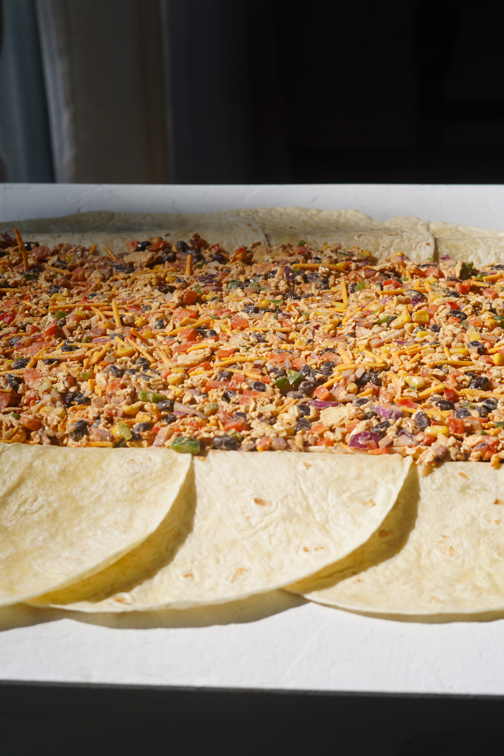 vegan quesadillas mixture spread inside the tortillas on a sheet pan