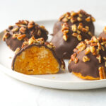 pumpkin pie bites on a white plate with one cut in half exposing the inside