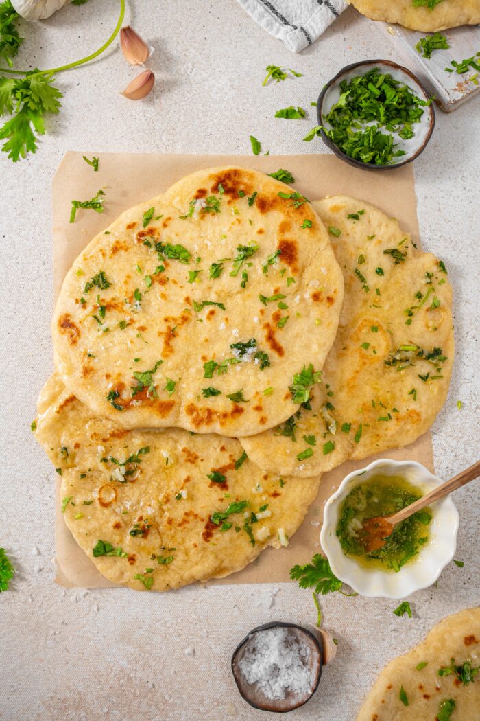 high protein flatbread on top of baking parchment with a dish of garlic coriander butter on the side
