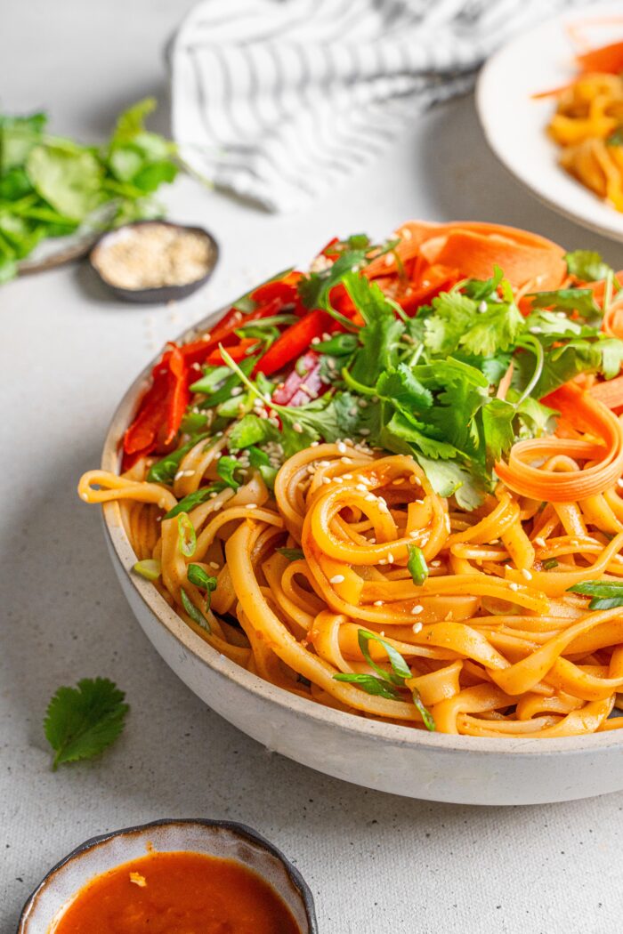 fiery gochujang noodles served in a white bowl with frehs veggies