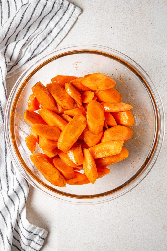 Cliced carrots in a glass bowl drizzled with the glaze.