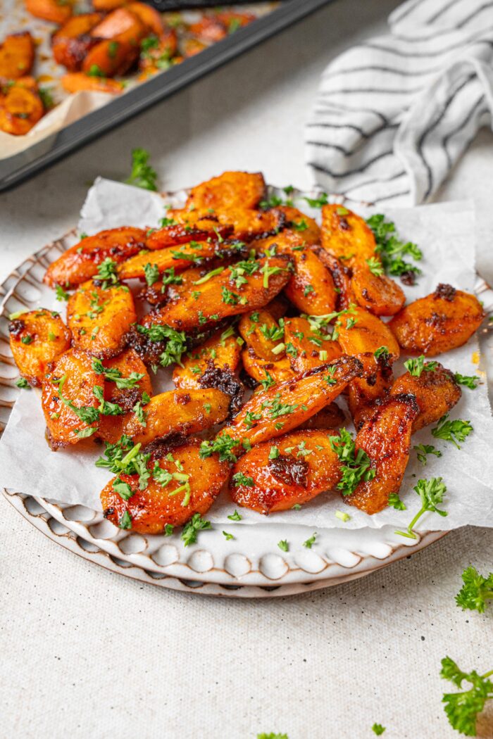 Maple glaze carrots served on a plate with fresh herbs.