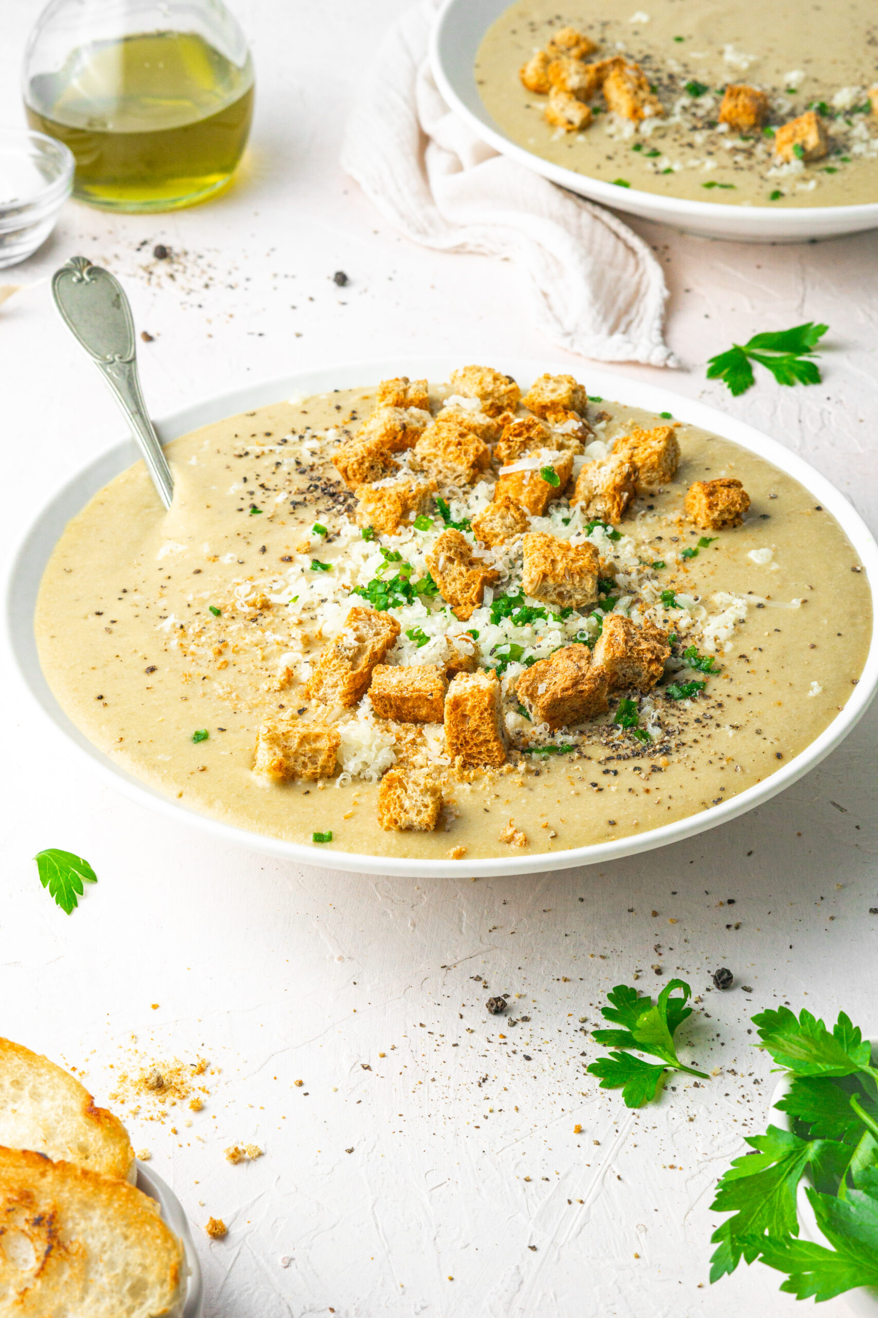 30 clove garlic soup served with choves, vegan parmesan and croutons in a white bowl