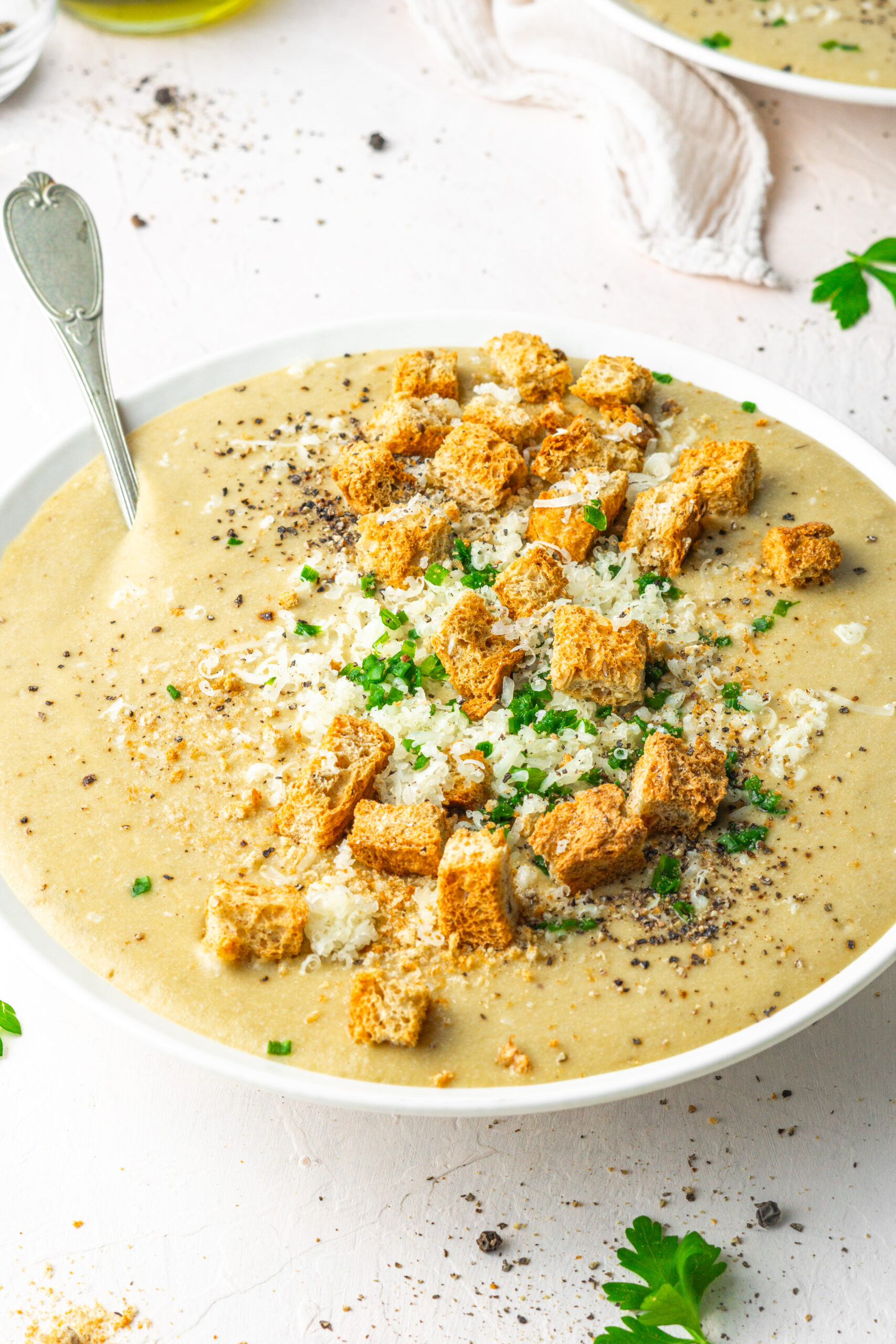 30 clove garlic soup served with choves, vegan parmesan and croutons in a white bowl