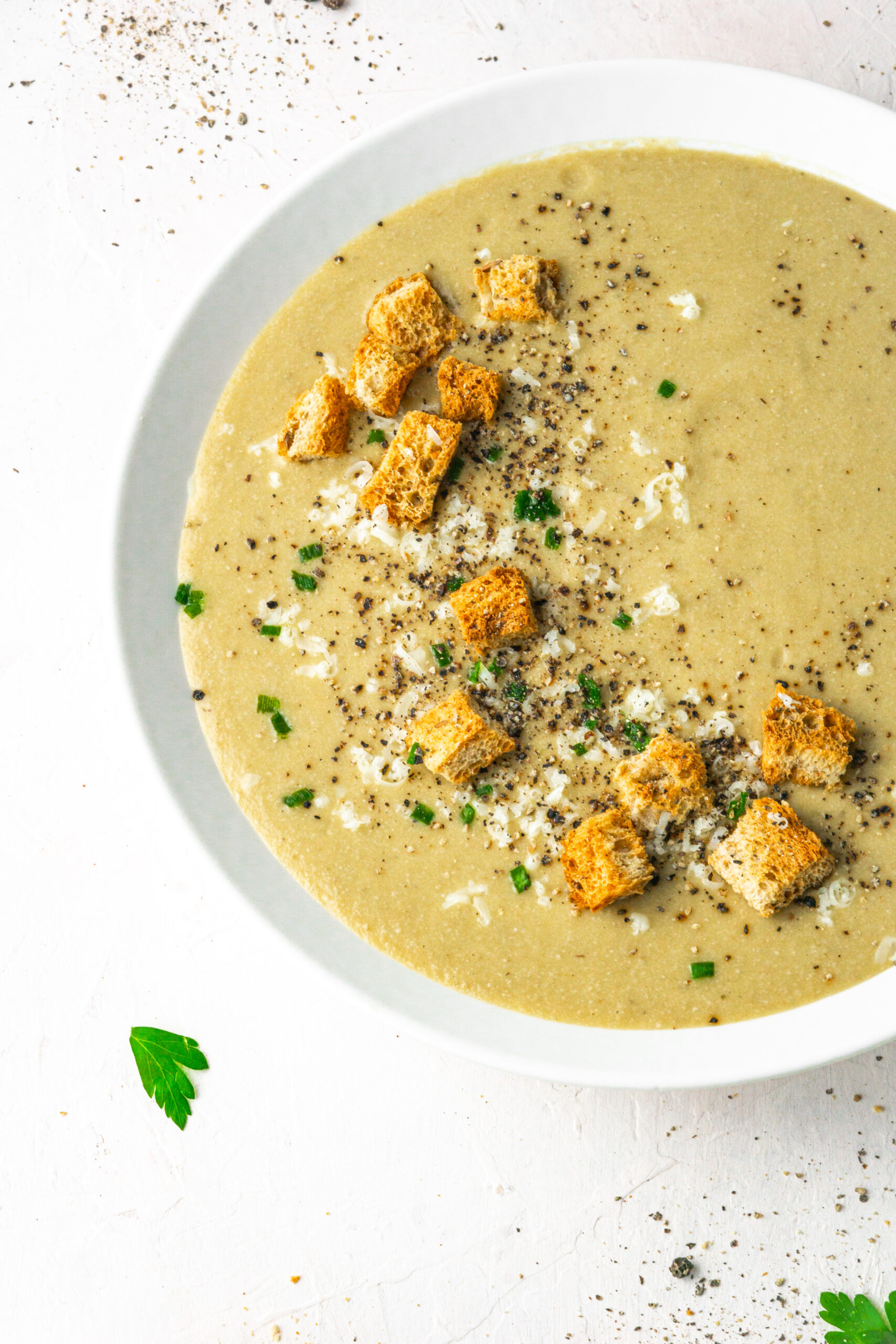 30 clove garlic soup served with choves, vegan parmesan and croutons in a white bowl