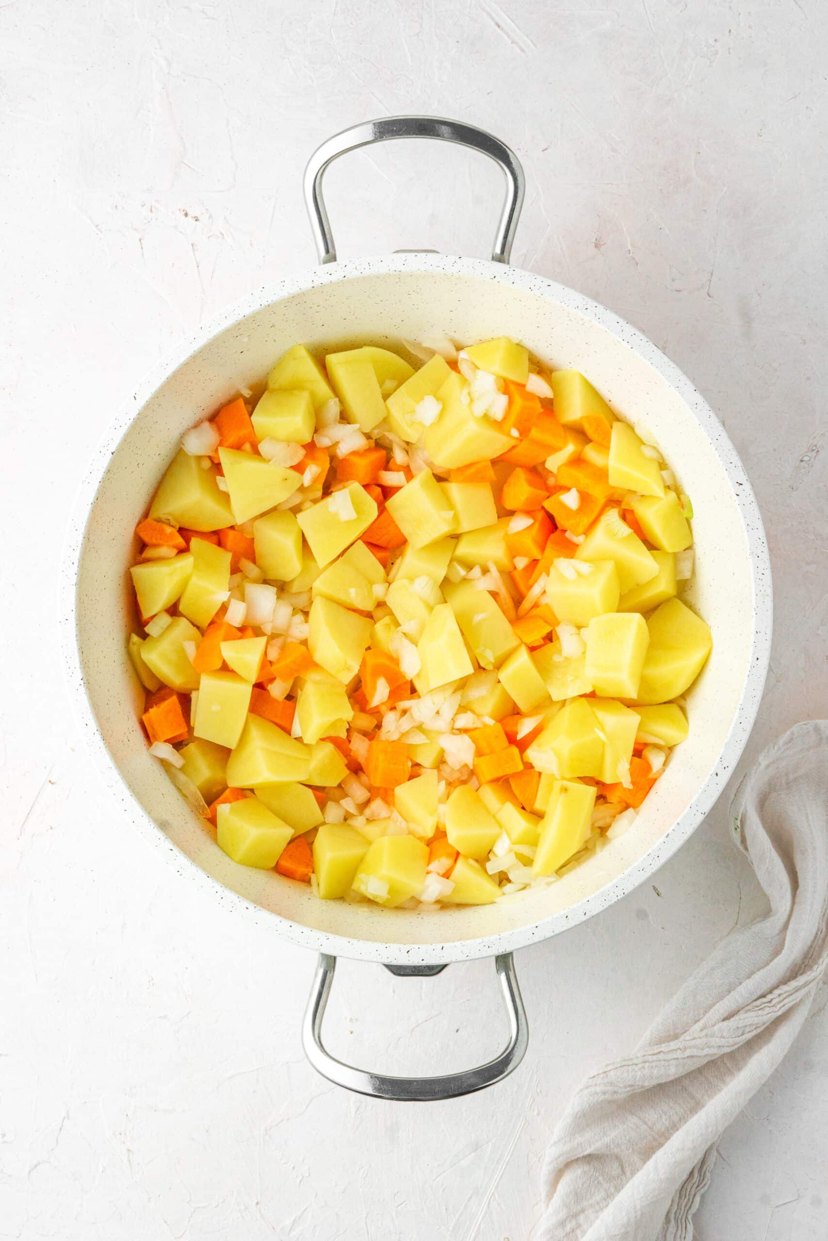 carrot potato and onions in a white pot