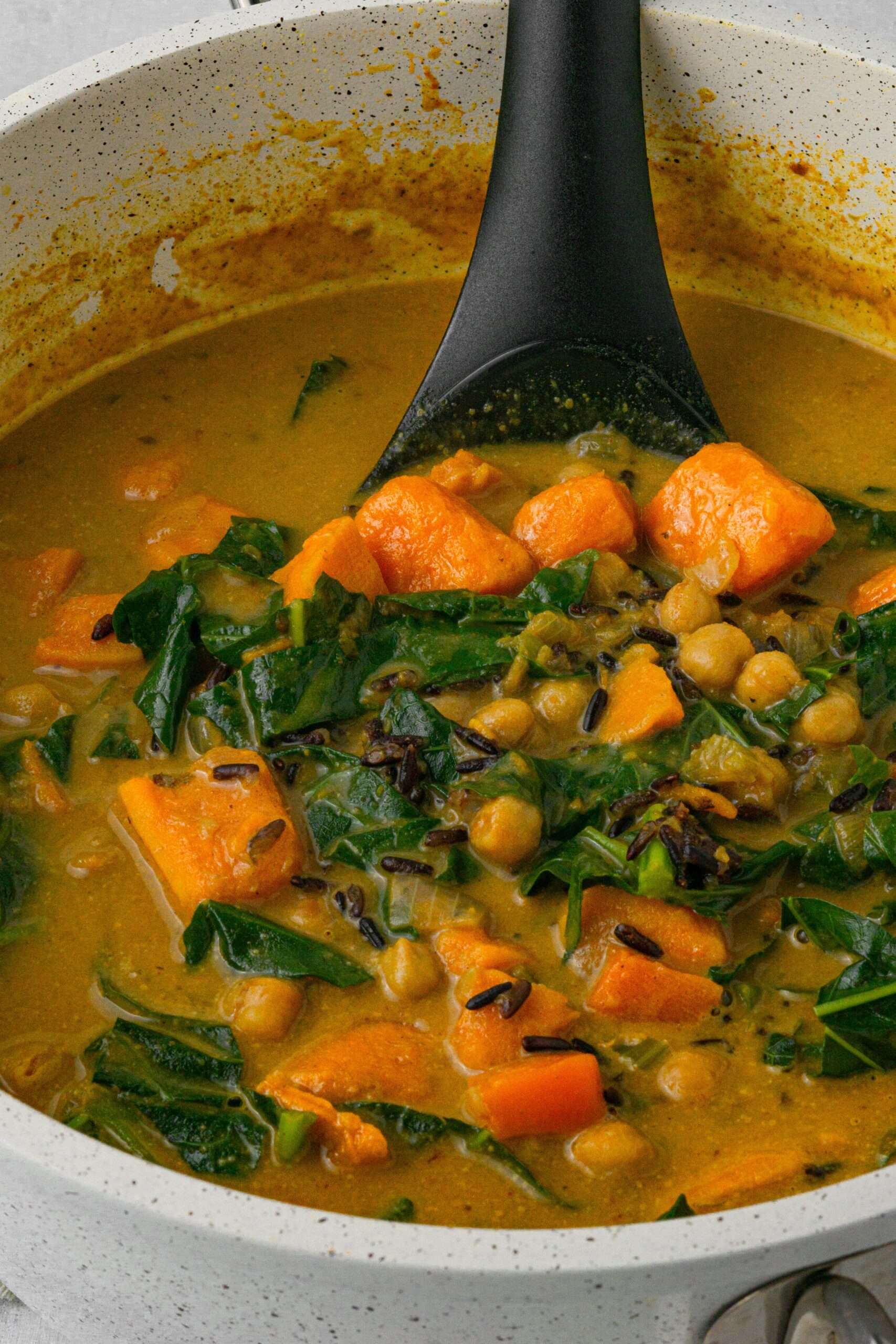 vegan creamy wild rice soup close up in the pot with ladke
