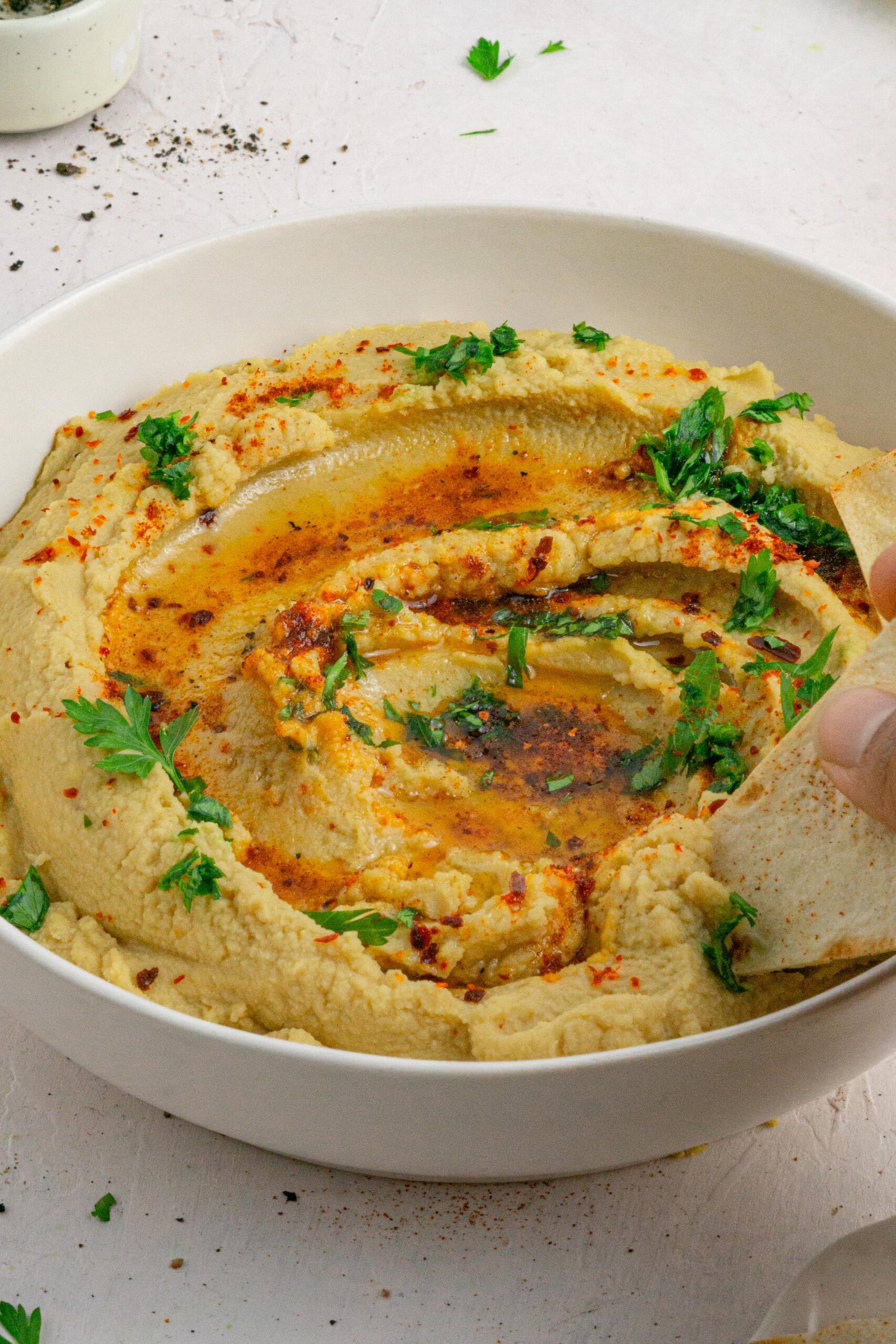 red lentil hummus with tortilla chips being dipped into the bowl