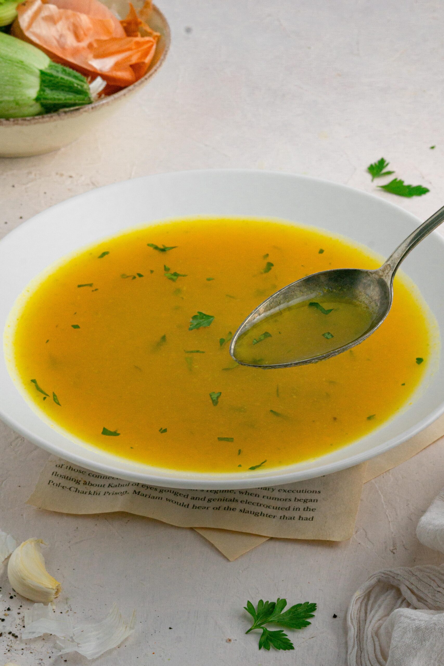 a spoonful of hidden veggie broth held up with the bowl in the background
