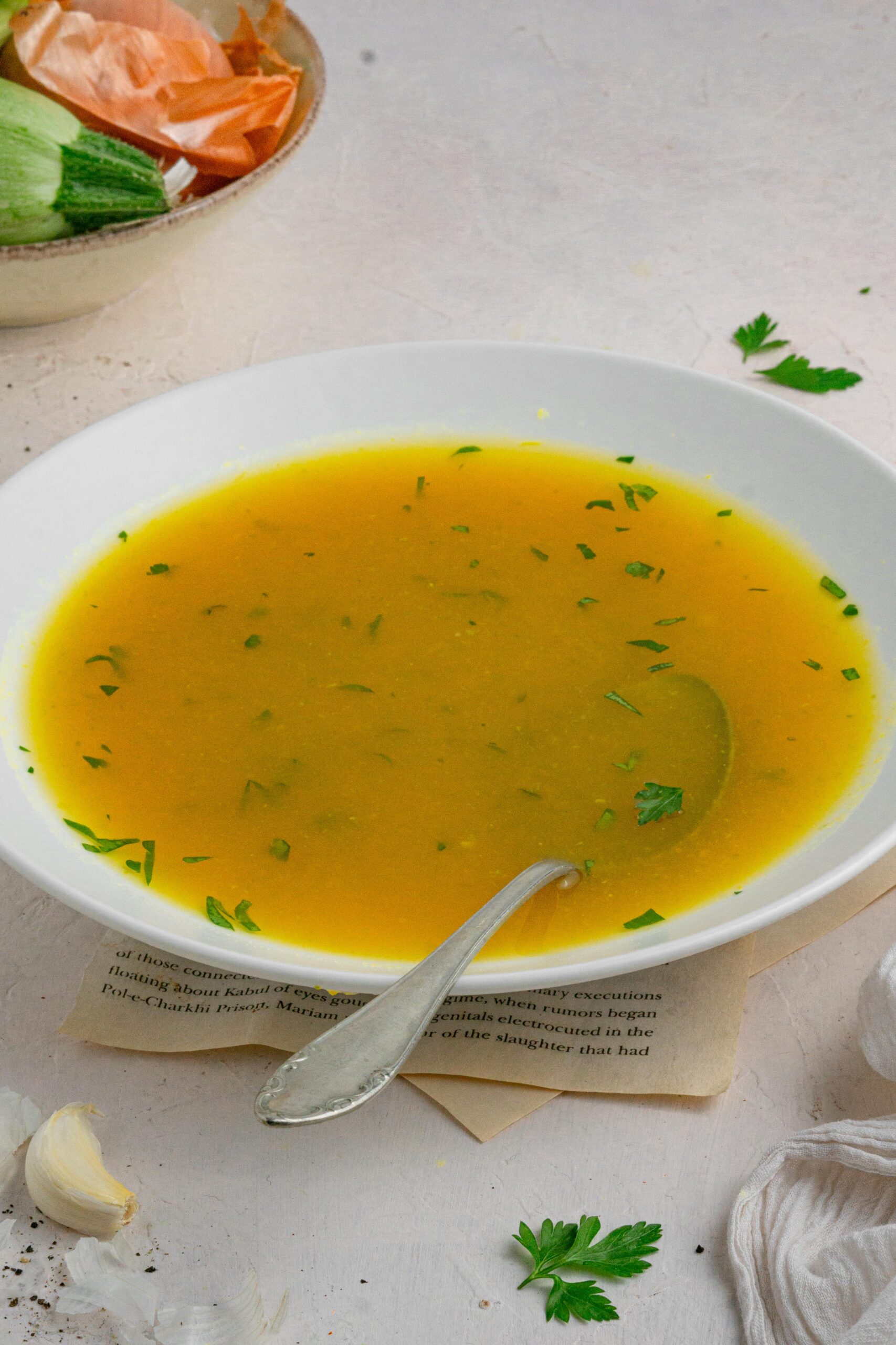 hidden veggie broth in a white bowl with the spoon submerged
