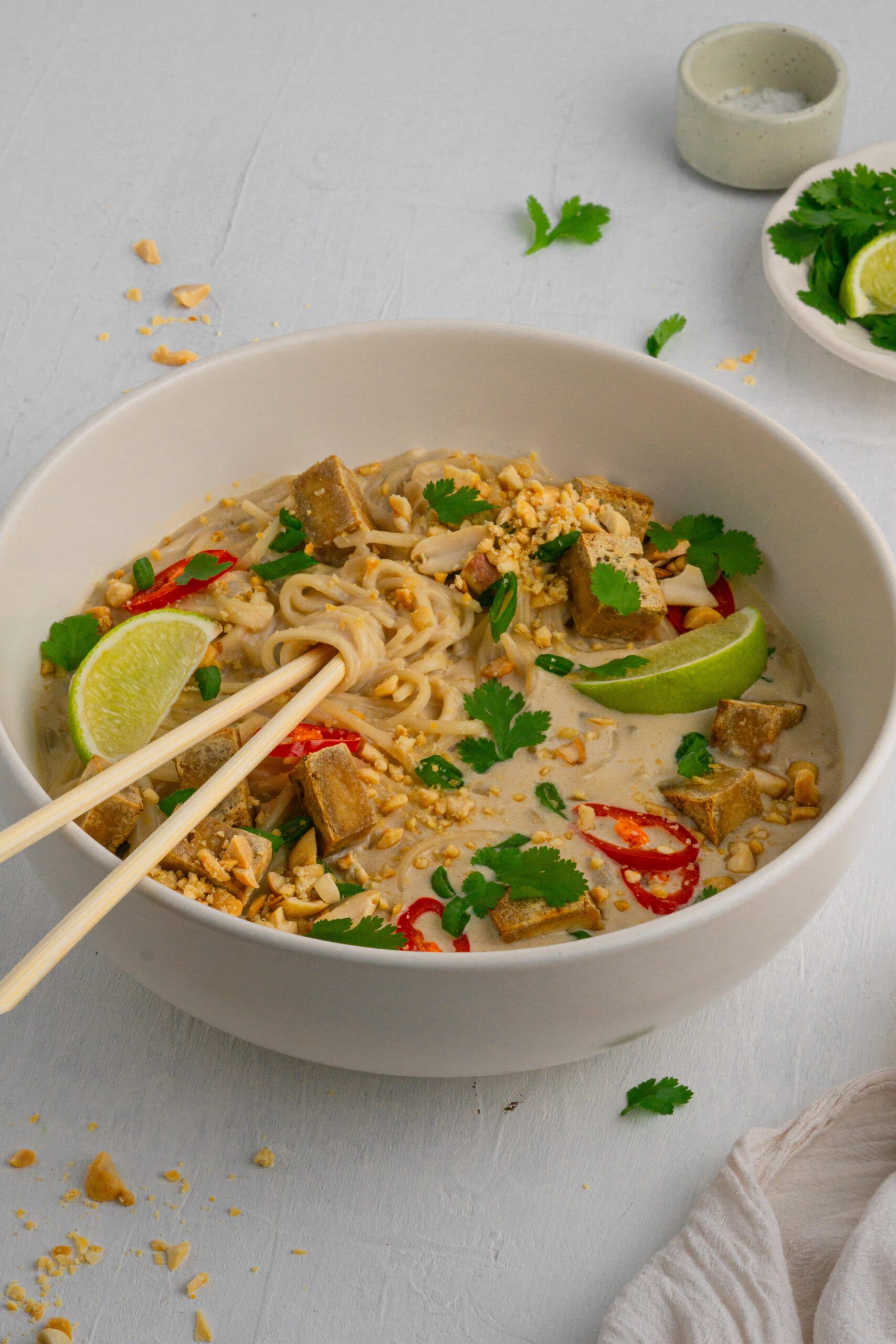 Peanut butter ramen noodles served in a large white bowl with chopsticks sticking out