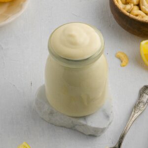 healthy vegan mayonnaise in a small jar on top of marble coaster