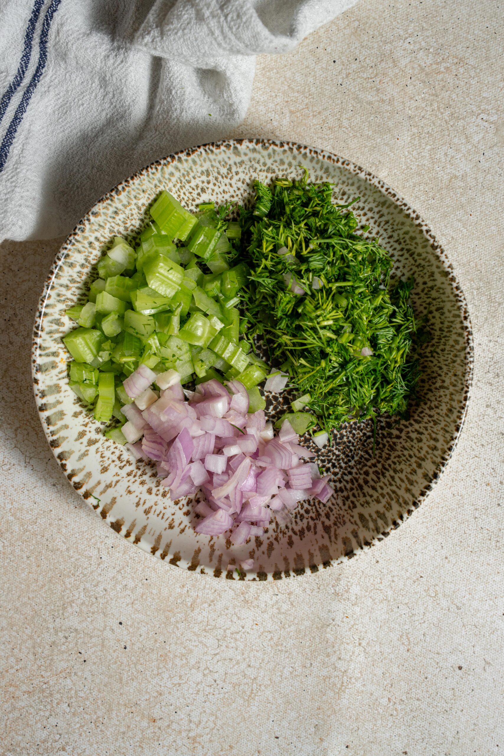 dill celery and red onion in a ceramic bowl