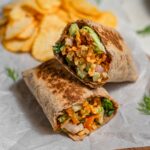 shredded tofu wrap cut in half with chips in the background