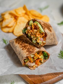 shredded tofu wrap cut in half with chips in the background