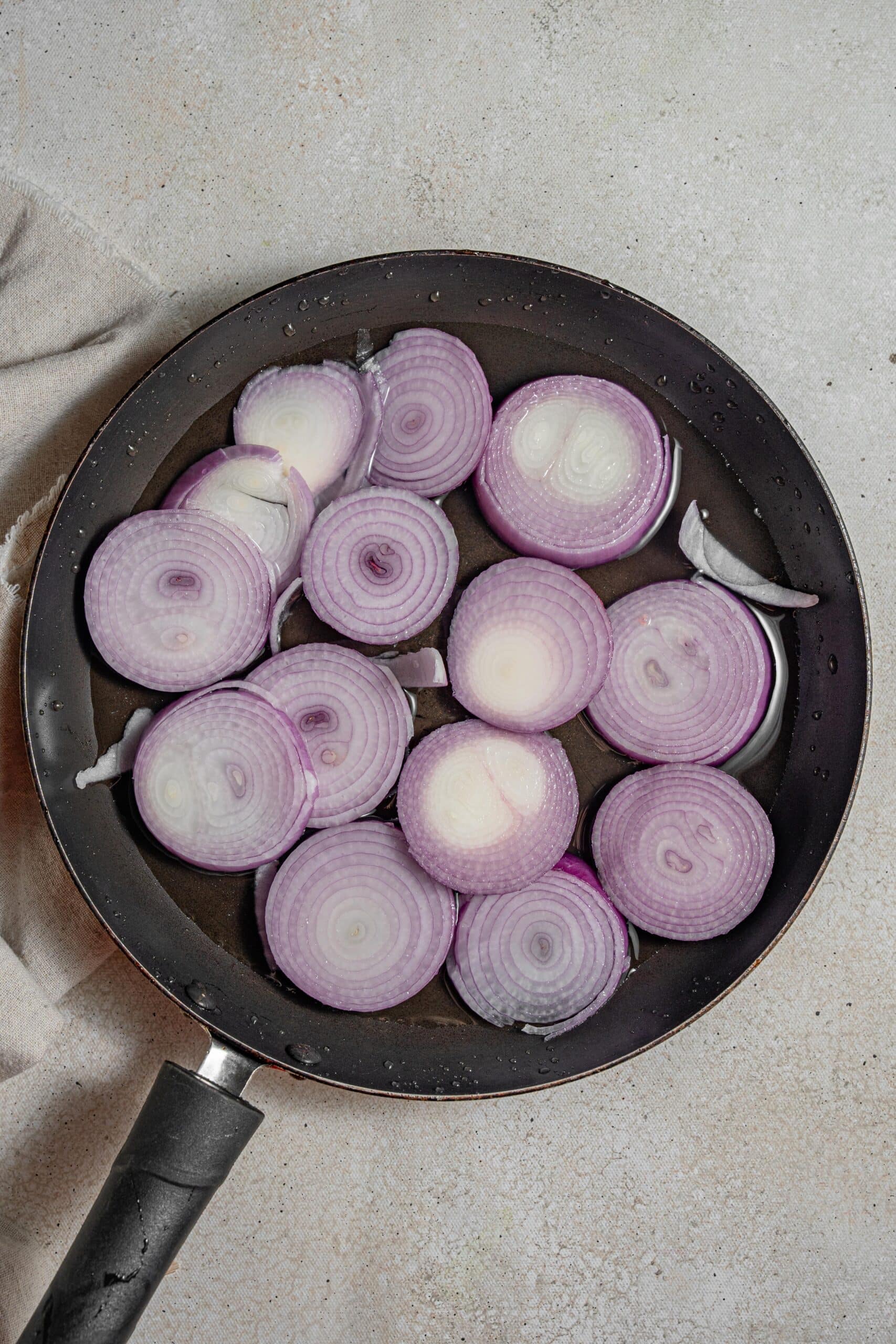 red onions in a frying pan with enough water to cover them