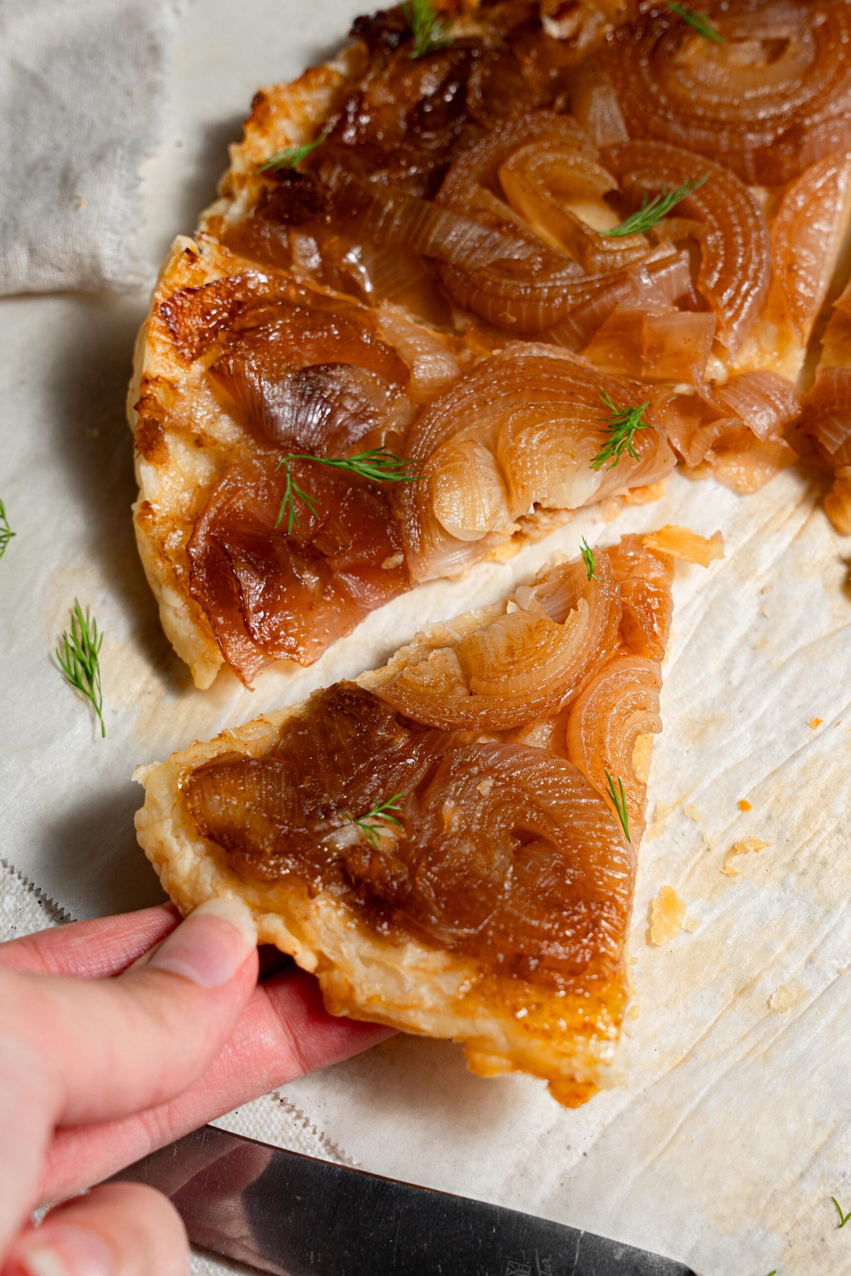 picking up a slice of vegan caramelized onion tart