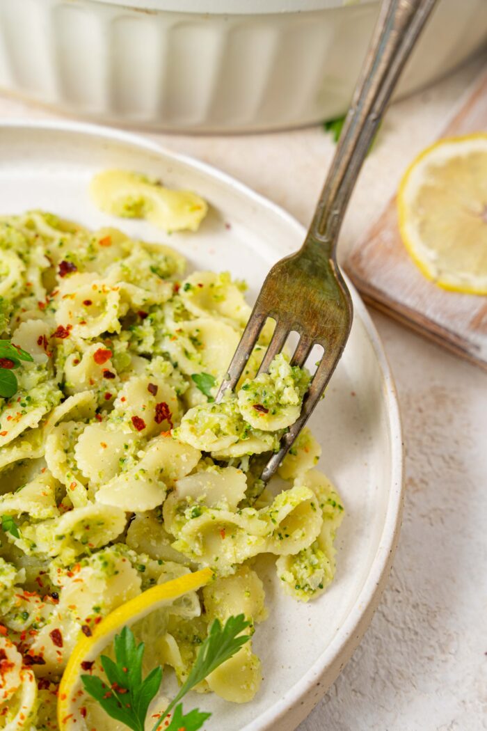 a fork picking up some easy broccoli pasta off a white plate