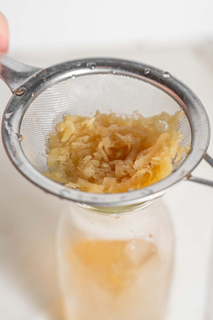 ginger pulp being strained in a fine mesh sieve