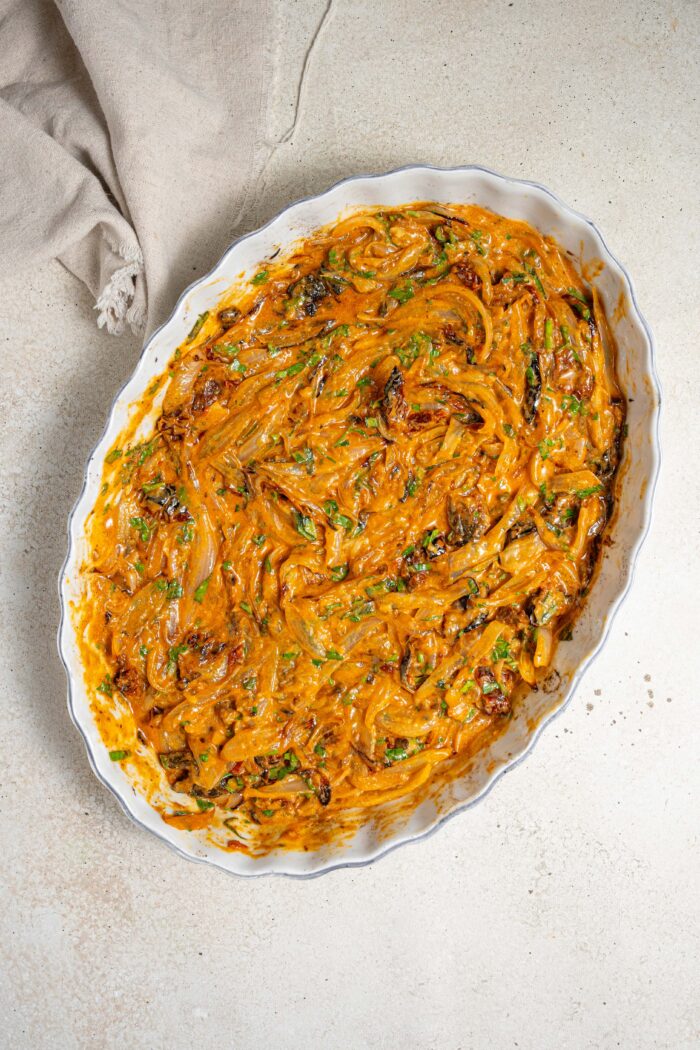 caramelized onions mixed with the sauce in a casserole dish