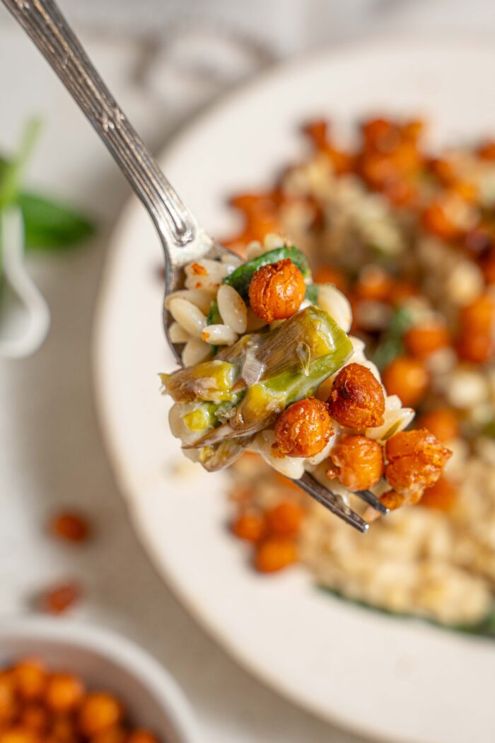 a close up of a fork with creamy lemon orzo