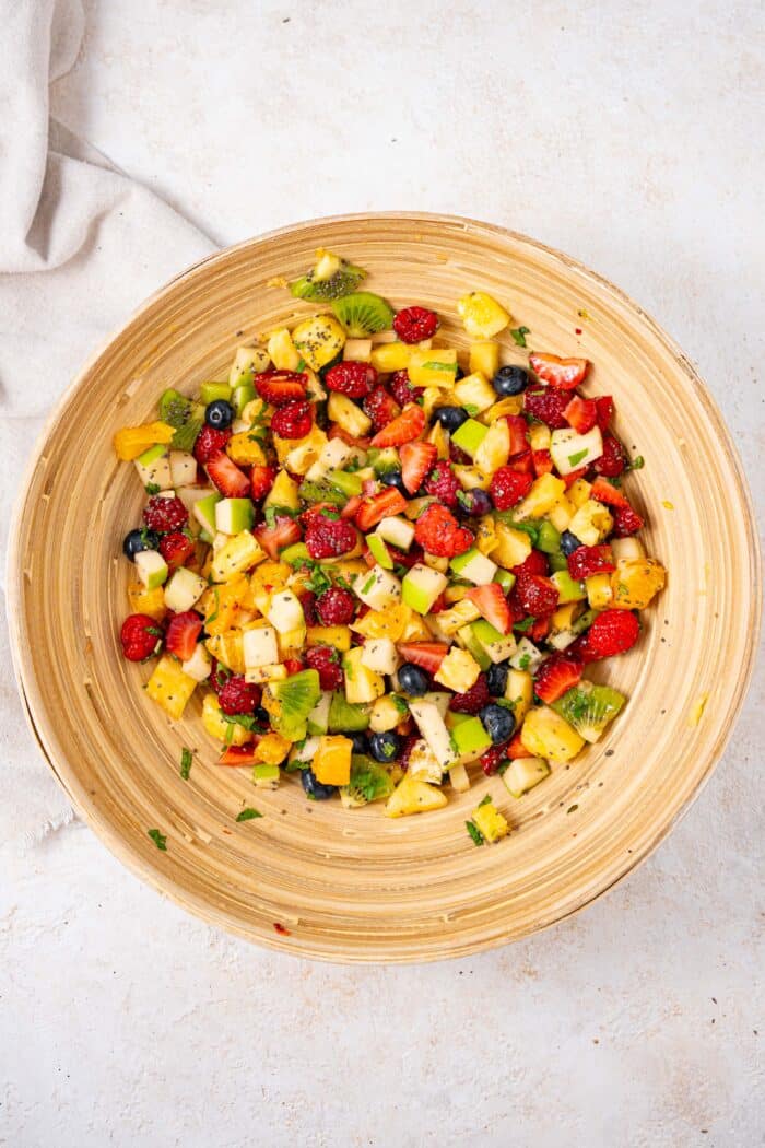 fruits salad mixed together in a wooden salad bowl